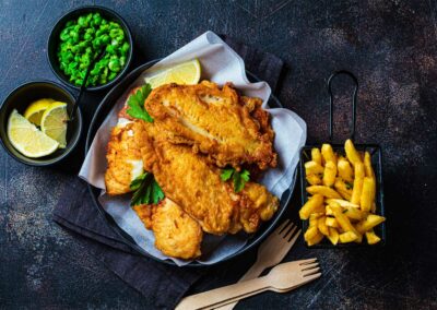 fish and chips with green peas on dark background