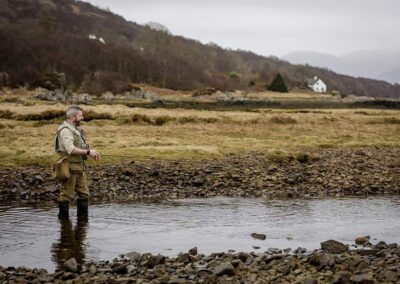 A fisherman is standing in water in a river near Kinloch Lodge on the Isle of Skye. Used to illustrate the UK Fishing Vacations page of the Turas Travel website.
